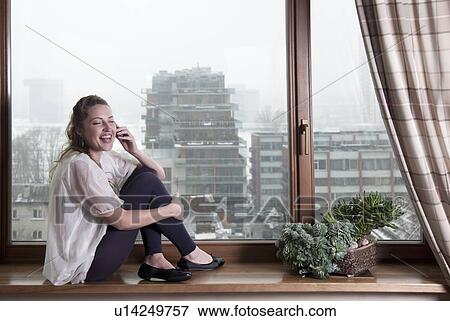 Woman talking on phone at windowsill View Large Photo Image Stock Photo - Woman talking on phone at windowsill. Fotosearch