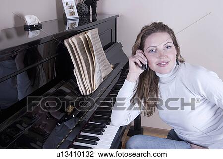Woman talking on phone by piano View Large Photo Image Stock Image - Woman talking on phone by piano. Fotosearch