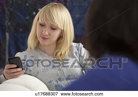 Stock Photo - Woman texting on mobile phone in company. Fotosearch
