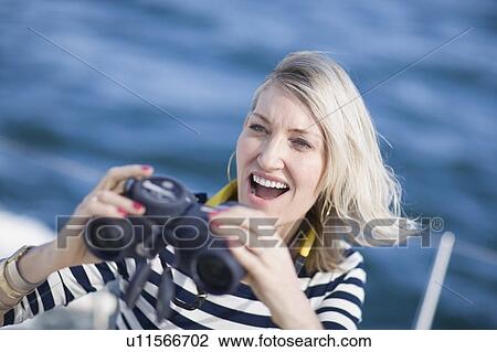 Stock Image - Woman using binoculars on boat. Fotosearch