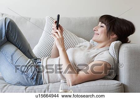 Woman using cell phone on couch View Large Photo Image Picture - Woman using cell phone on couch. Fotosearch