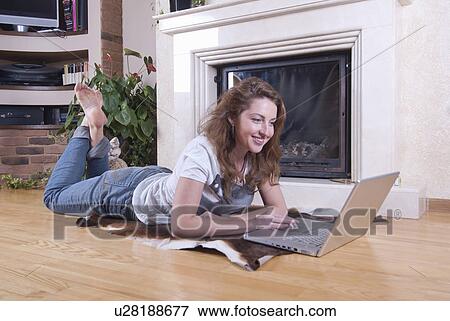 Woman using laptop in living room View Large Photo Image Stock Photo - Woman using laptop in living room. Fotosearch