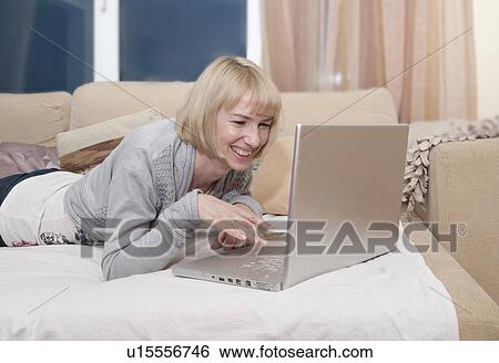 Woman using laptop on couch View Large Photo Image Stock Photograph - Woman using laptop on couch. Fotosearch