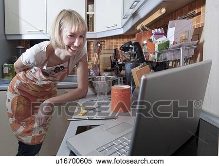 Woman using laptop to cook in kitchen View Large Photo Image Stock Photography - Woman using laptop to cook in kitchen. Fotosearch