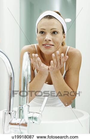 Stock Photo - Woman washing her face in bathroom. Fotosearch