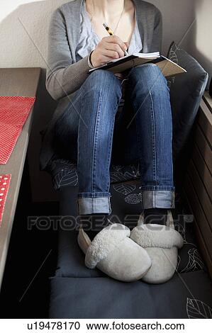 Stock Image - Woman wearing sheep sking slippers. Fotosearch