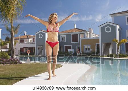 Woman with arms stretched out by pool View Large Photo Image Stock Photo - Woman with arms stretched out by pool. Fotosearch