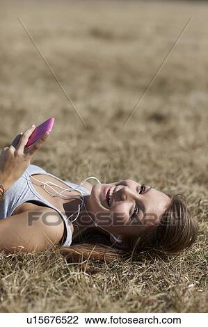 Stock Image - Woman with cellphone in meadow. Fotosearch