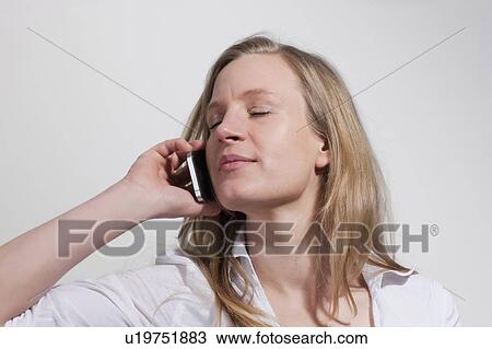 Stock Image - Woman with closed eyes with Cellphone. Fotosearch