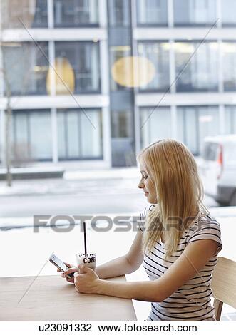 Stock Image - Woman with coffee and cellphone. Fotosearch
