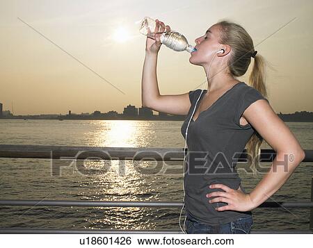 Woman with mp3 player, drinking water View Large Photo Image Stock Photograph - Woman with mp3 player, drinking water. Fotosearch