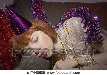 Stock Photography - woman with party hat asleep on sofa. Fotosearch