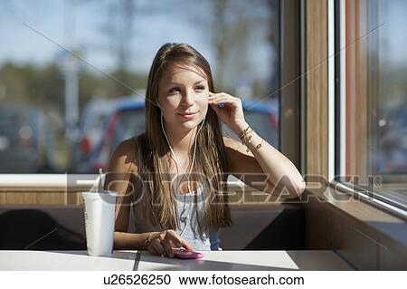 Stock Image - Woman with softdrink and headset. Fotosearch