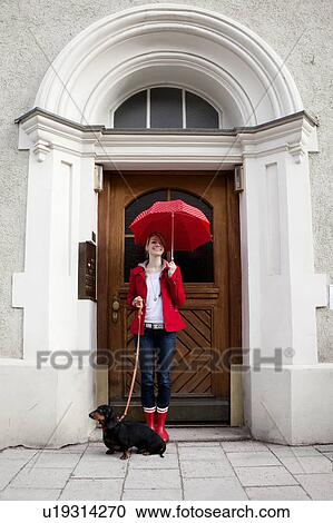 Stock Image - Woman with umbrella and sausage dog. Fotosearch