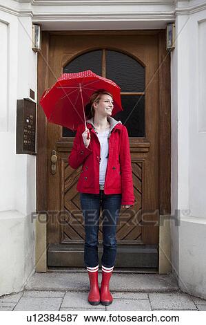 Stock Photo - Woman with umbrella in front of house. Fotosearch