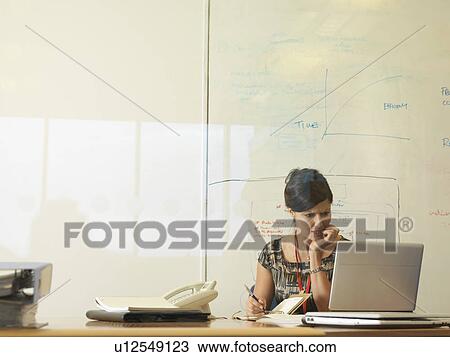 Stock Image - Woman working at desk. Fotosearch