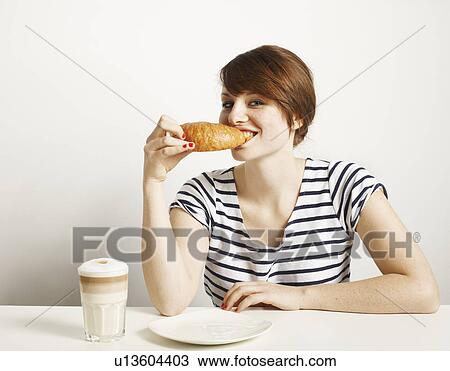 Stock Image - Women eating Croissant smiling. Fotosearch