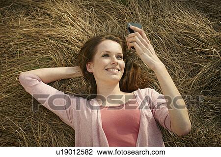 Women lying in meadow with cellphone View Large Photo Image Stock Image - Women lying in meadow with cellphone. Fotosearch