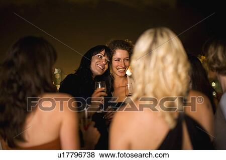 Stock Photo - Women smiling at party at night. Fotosearch
