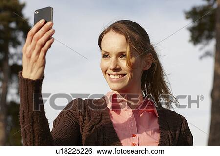 Stock Photograph - Women taking selfportrait with cellphone. Fotosearch