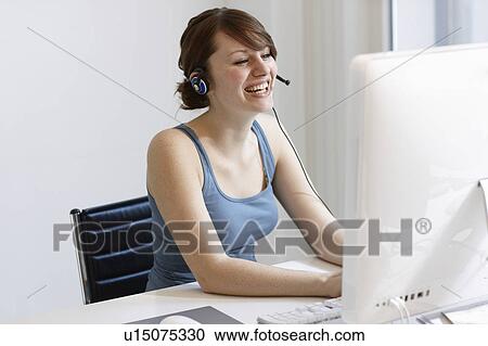 Stock Image - Women with Headset working on Computer. Fotosearch