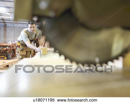 Stock Photography - Woodworker sawing timber. Fotosearch