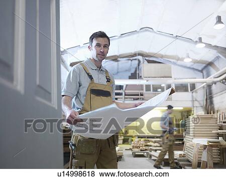 Stock Photo - Woodworker with plans in workshop. Fotosearch