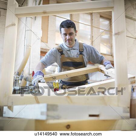 Stock Image - Woodworker with window frames. Fotosearch