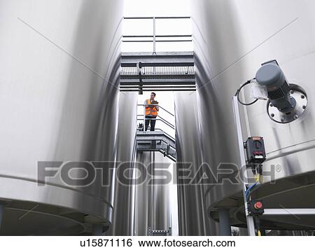 Worker checking tanks in bottling plant View Large Photo Image Stock Photograph - Worker checking tanks in bottling plant. Fotosearch