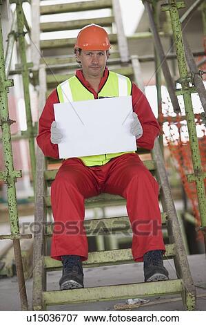 Worker holding an empty sheet of paper View Large Photo Image Stock Photo - Worker holding an empty sheet of paper. Fotosearch