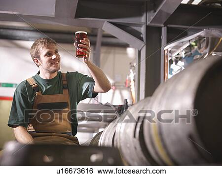 Worker holding pint of beer in brewery View Large Photo Image Stock Photograph - Worker holding pint of beer in brewery. Fotosearch
