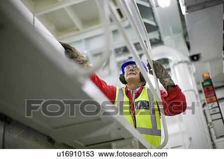 Stock Image - Worker in engine room. Fotosearch