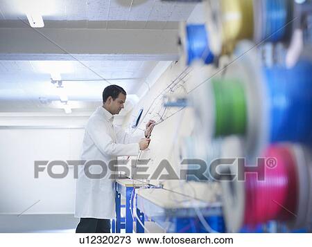 Stock Image - Worker making up wiring loom. Fotosearch