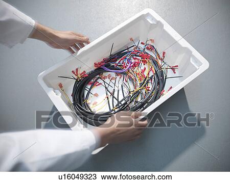 Stock Image - Worker picking up box of cables. Fotosearch