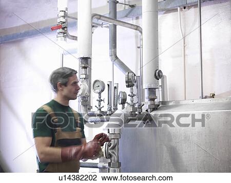 Worker turning valve in brewery View Large Photo Image Stock Image - Worker turning valve in brewery. Fotosearch