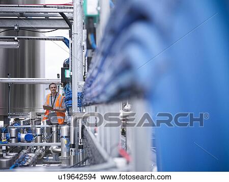 Worker with machinery in bottling plant View Large Photo Image Picture - Worker with machinery in bottling plant. Fotosearch