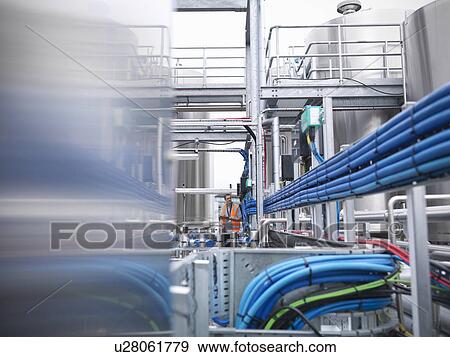 Stock Photo - Worker with machinery in bottling plant. Fotosearch