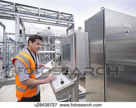 Stock Photo - Worker with machinery in bottling plant. Fotosearch