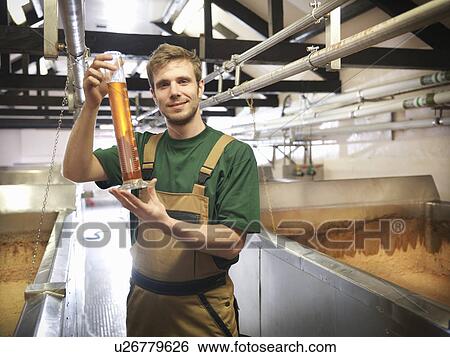 Stock Photograph - Worker with sample in fermentation room. Fotosearch