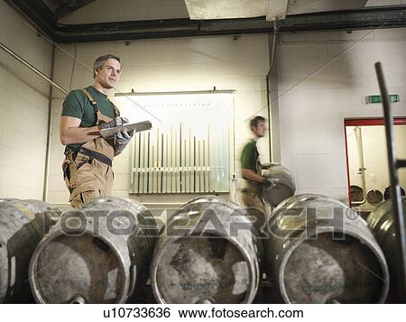 Stock Photograph - Workers in brewery with barrels. Fotosearch