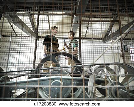 Stock Image - Workers in grain mill in brewery. Fotosearch