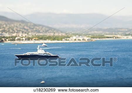 Stock Photo - Yacht sailing by urban coastline. Fotosearch