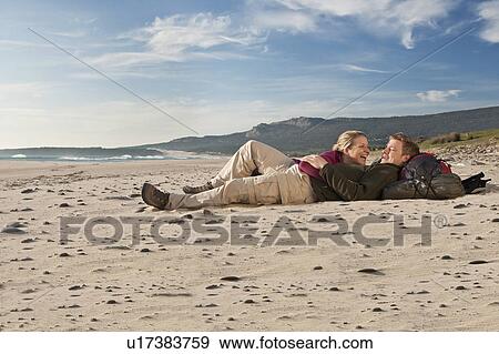 Stock Photo - Young backpackers lying on beach. Fotosearch