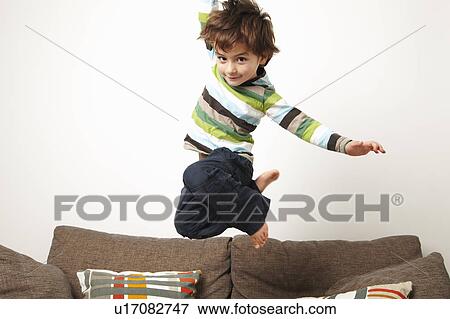 Young boy jumping on sofa View Large Photo Image Stock Photo - Young boy jumping on sofa. Fotosearch