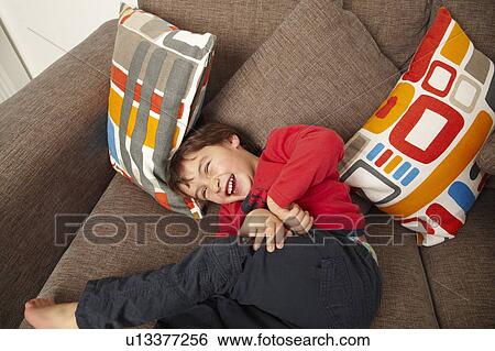 Young boy laughing on sofa View Large Photo Image Stock Photograph - Young boy laughing on sofa. Fotosearch
