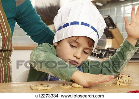 Picture - Young boy making cookies in kitchen. Fotosearch