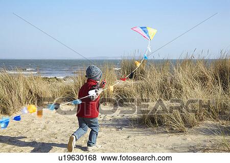 Young boy running towards sea with kite View Large Photo Image Stock Photo - Young boy running towards sea with kite. Fotosearch