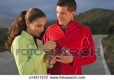 Stock Image - Young couple holding water bottles. Fotosearch