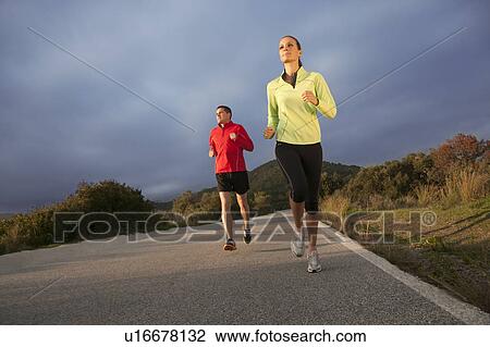 Stock Image - Young couple jogging in rural setting. Fotosearch