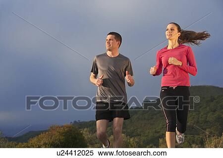 Stock Photography - Young couple jogging in rural setting. Fotosearch
